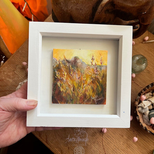 miniature framed oil painting of grasses in a sunlit meadow at golden hour in white frame
