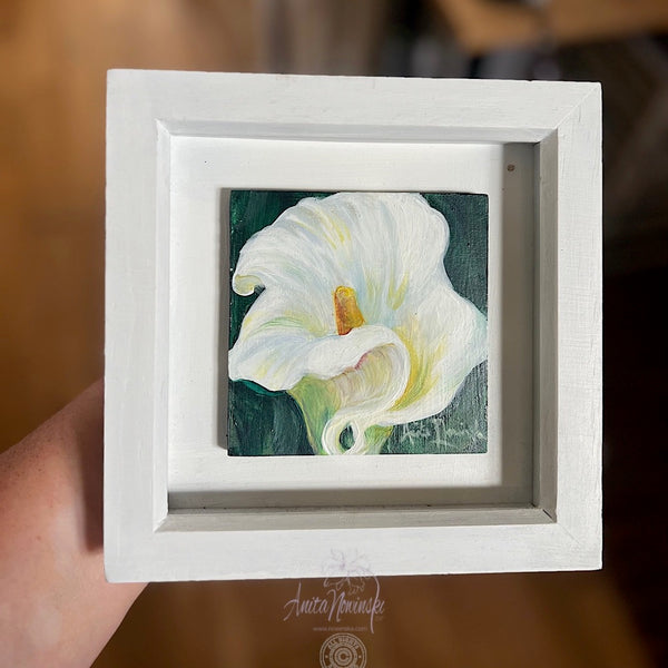 Framed artwork of a white peace lily flower with a green background