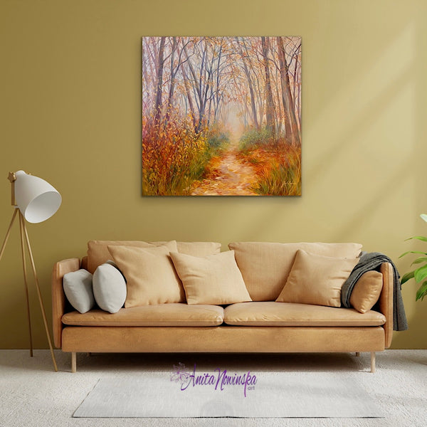 big landscape painting of an autumn woodland with a misty path by anita nowinska in a yellow ans beige room